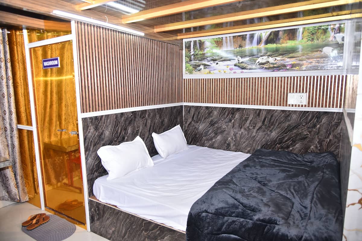 Una habitación de hotel con cama, zona de ducha y un mural de cascada.