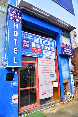 A hotel with signs indicating AC & NON AC rooms, a 24/7 availability, and a warning against narcotics control.