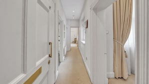 A hallway with white walls, beige carpet, and a beige curtain on the right. - Hertford Flat 4 (London)