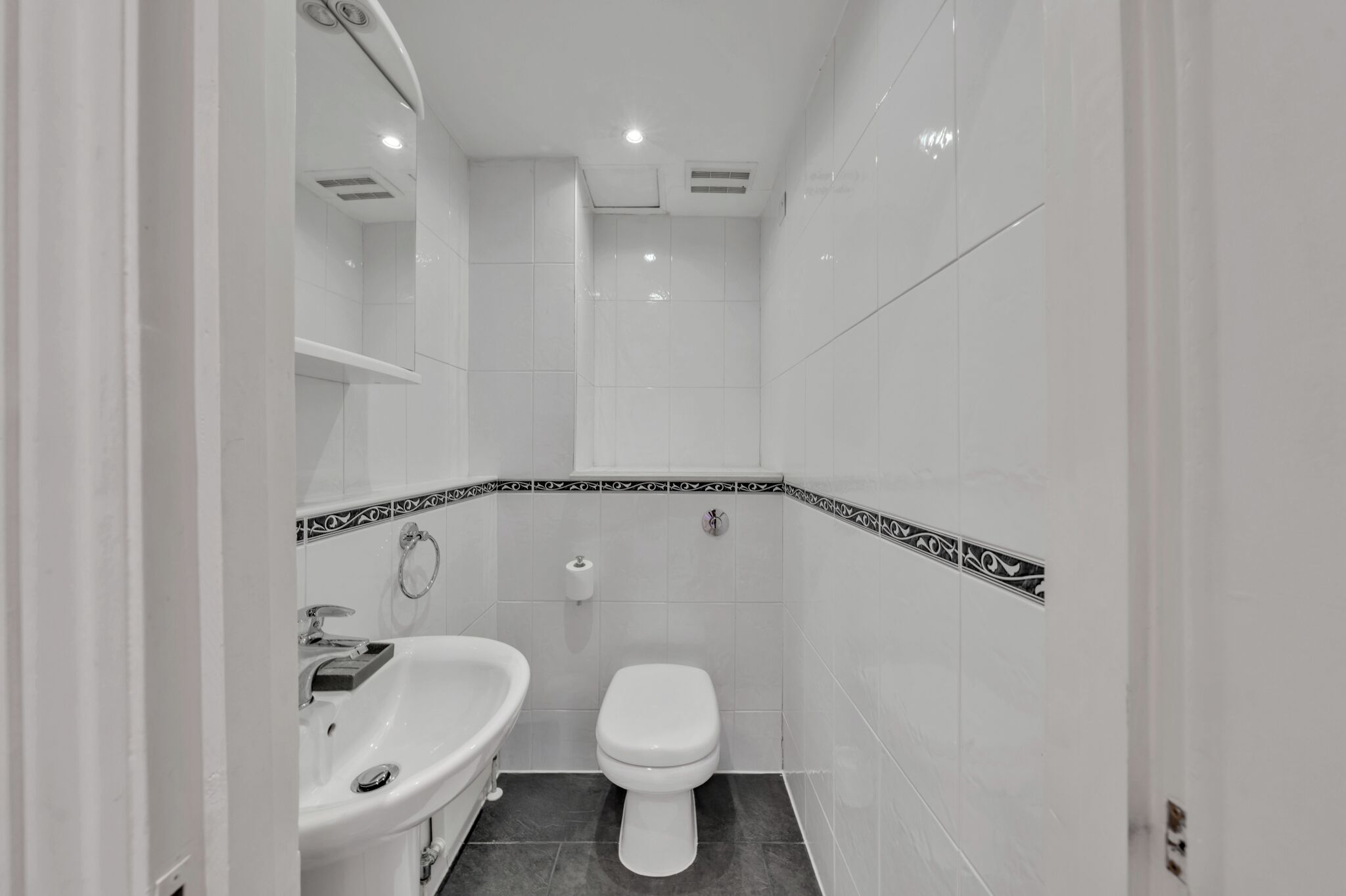 A small, white bathroom with a toilet, sink, and shower.
