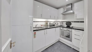 A modern kitchen with white cabinets, stainless steel appliances, and a black countertop. - Hertford Flat 4 (London)