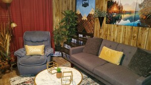 Ein gemütliches Wohnzimmer mit einem grauen Sessel, einer grauen Couch und einem runden Couchtisch mit weißem Marmorbelag.