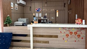 A reception desk with a clock, a small Christmas tree, and a sign for MTGA Inn. - OYO 91290 Cozitel (Bintulu)