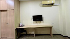A small room with a desk, a chair, a television, and an air conditioning unit. - OYO 91290 Cozitel (Bintulu)
