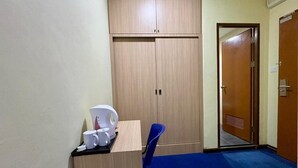 A room with a wooden wardrobe, a desk with a coffee maker, and a blue carpet. - OYO 91290 Cozitel (Bintulu)