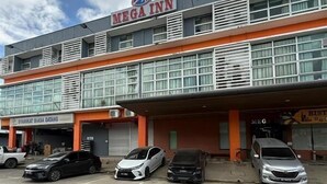 A multi-story building with a sign for 'MEGA INN' on the top. There are several cars parked in front. - OYO 91290 Cozitel (Bintulu)