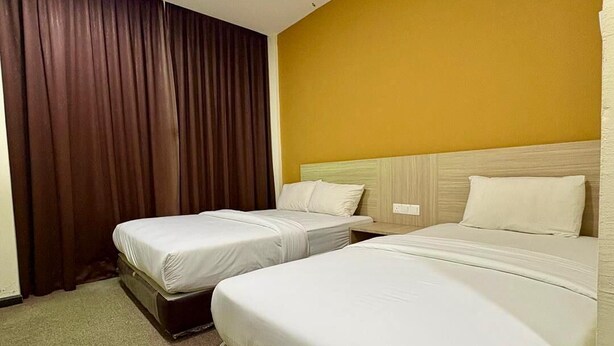 A hotel room with two beds, a wooden headboard, and a yellow wall. - OYO 91290 Cozitel (Bintulu)