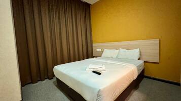 Una habitación de hotel con una cama, cortinas y una pared amarilla.