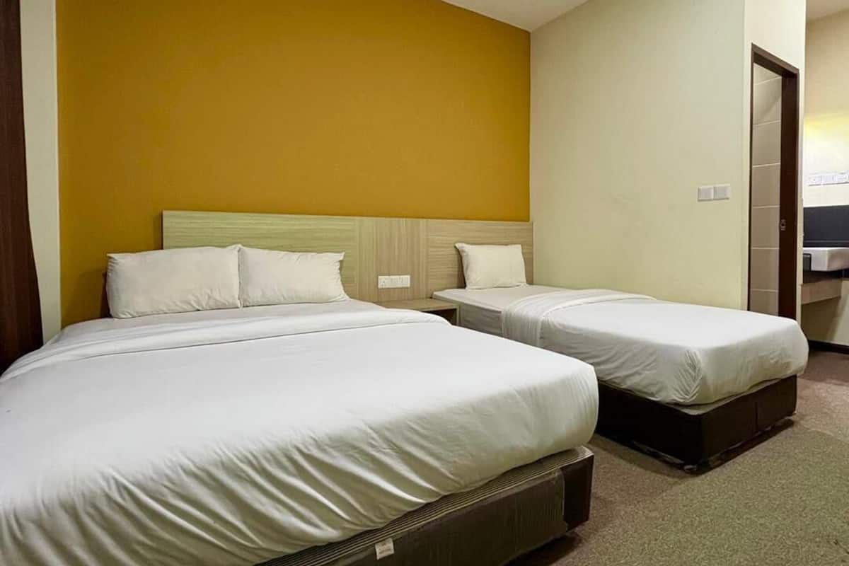 A hotel room with two beds, a wooden headboard, and a yellow accent wall.