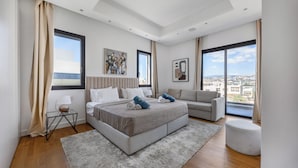 Camera moderna con un letto grande, un divano, un tavolino e vista sulla città.