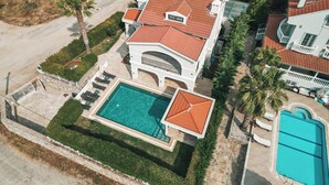 A large house with a swimming pool, a tennis court, and a garden.