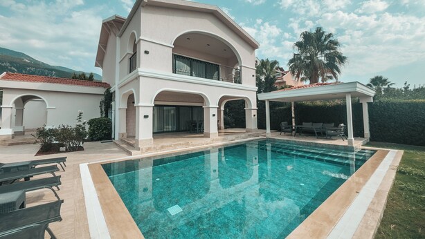 A two-story house with a swimming pool, outdoor seating, and a covered patio.