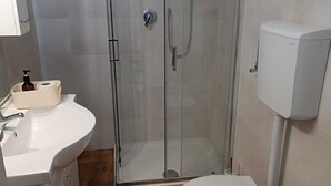 Ein kleines Badezimmer mit Dusche, Toilette, Waschbecken und Bidet.