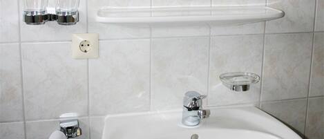 A bathroom with a sink, mirror, and two glasses on a shelf.