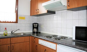 Une cuisine avec des meubles en bois, un évier en acier inoxydable, une machine à café, un four à micro-ondes et une cuisinière.