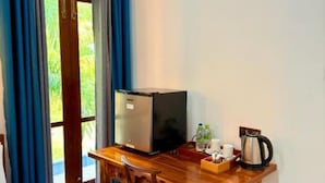 A compact room with a wooden desk, a refrigerator, a kettle, and a coffee maker. - Devon Surf . Inn : Deluxe Family Room (Dikwella)