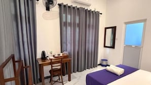 A hotel room with a bed, a desk with a chair, a window, and curtains. - Devon Surf Inn : Standard Double Room (Dikwella)