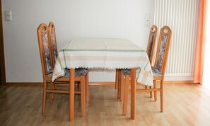 Et spisebord med dug med striber, omgivet af træstole med blomstret betræk.