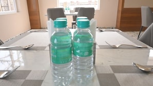 Une salle de conférence avec une table préparée pour une réunion, comprenant des bouteilles d’eau, des couverts et une vue sur l’extérieur.
