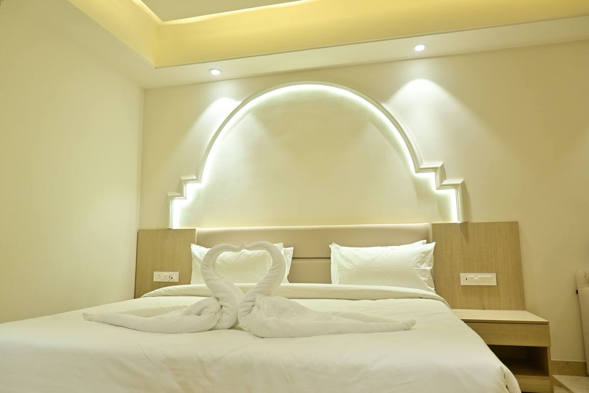 Ein Hotelzimmer mit einem großen Bett, einem Kopfteil im Halbmonddesign und zwei Nachttischen.