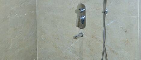 A bathroom with a shower, a toilet, and a wall-mounted towel rack.