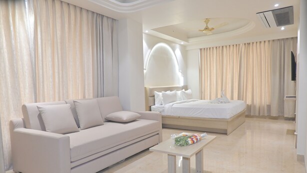 Une chambre d’hôtel moderne équipée d’un canapé, d’un lit, d’une petite table et d’un ventilateur de plafond.
