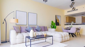A modern living room with a sofa, coffee table, and artwork on the wall. - Bloomfields 1BR Canal The View Raha (Abu Dhabi)