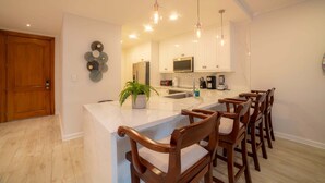 A modern kitchen with a central island, bar seating, and pendant lighting. - Del Mar 4M 3 bdr Garden View in Los Suenos (Jacó)