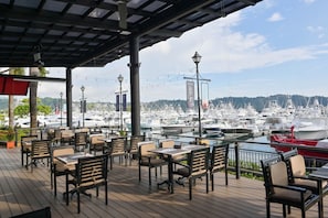 An outdoor dining area with tables and chairs, overlooking a marina with boats. - Del Mar 4M 3 bdr Garden View in Los Suenos (Jacó)