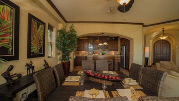 A dining area with a dark wooden table, wicker chairs, and a central fruit display.