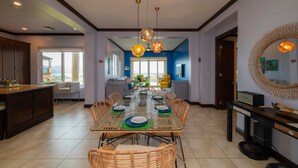 A spacious dining area with a long table set for six, surrounded by wicker chairs. - Altavista 4C 3 bdr Ocean View in Los Suenos (Jacó)