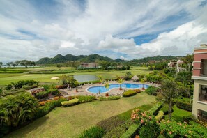 A resort with a pool, lush greenery, and a golf course in the background. - Del Mar 3C 3 bdr Ocean View in Los Suenos (Jacó)
