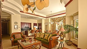 A spacious living room with a green sofa, a wooden coffee table, and a large window with curtains. - Bella Vista 4B 3 Bdrs Ocean View in Los Suenos (Jacó)