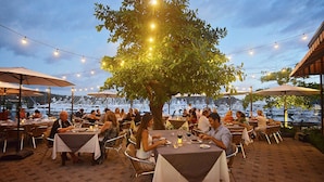 An outdoor dining area with tables and chairs, string lights, and umbrellas. - Del Mar 5J 3 bdr Garden View in Los Suenos (Jacó)