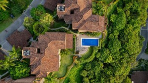 Un barrio residencial con varias casas, una piscina y abundante vegetación.