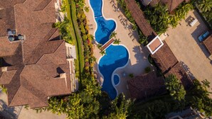 An aerial view of a residential area with multiple houses, a swimming pool, and surrounding greenery. - Bella Vista 3A 3 Bdrs Ocean View in Los Suenos (Jacó)