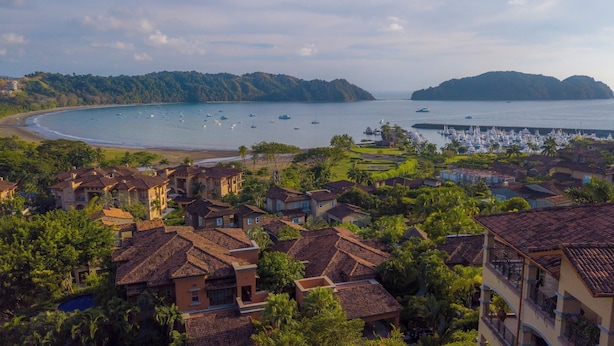 Zona residencial costera con casas, un puerto deportivo y una playa.