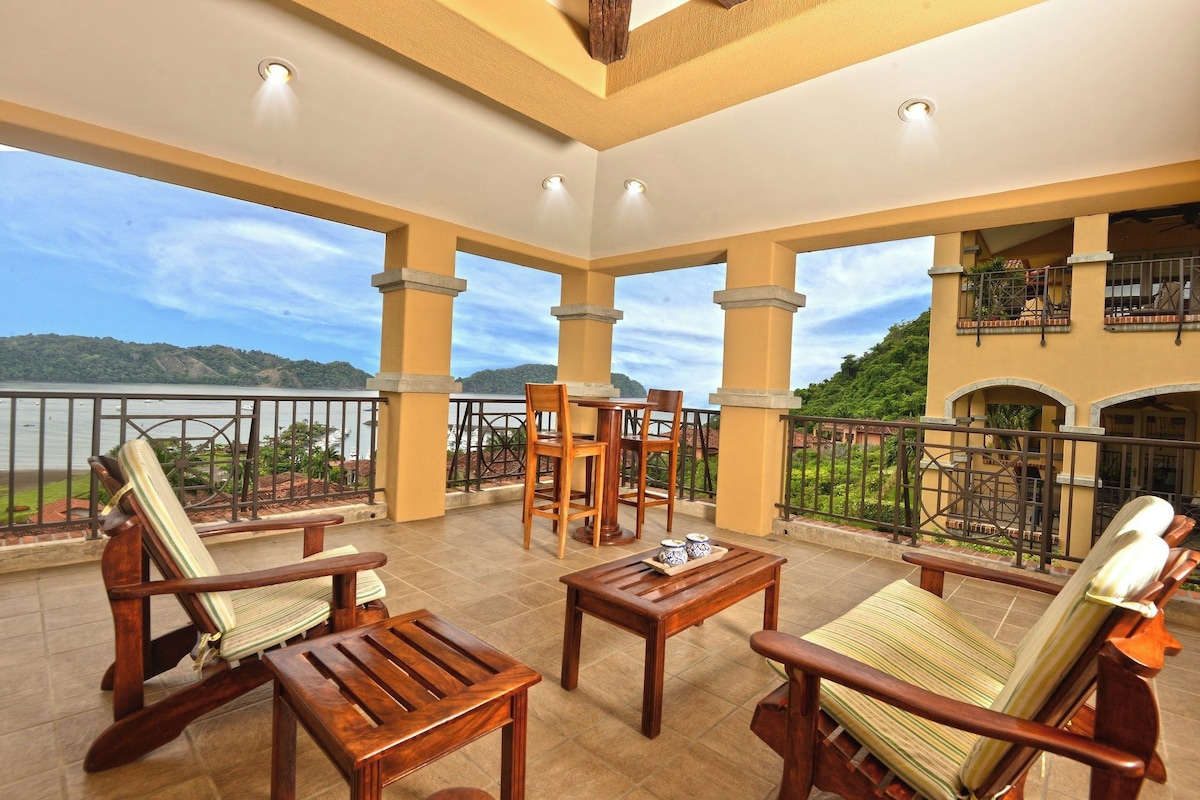 A spacious balcony with wooden furniture and a view of a lake.