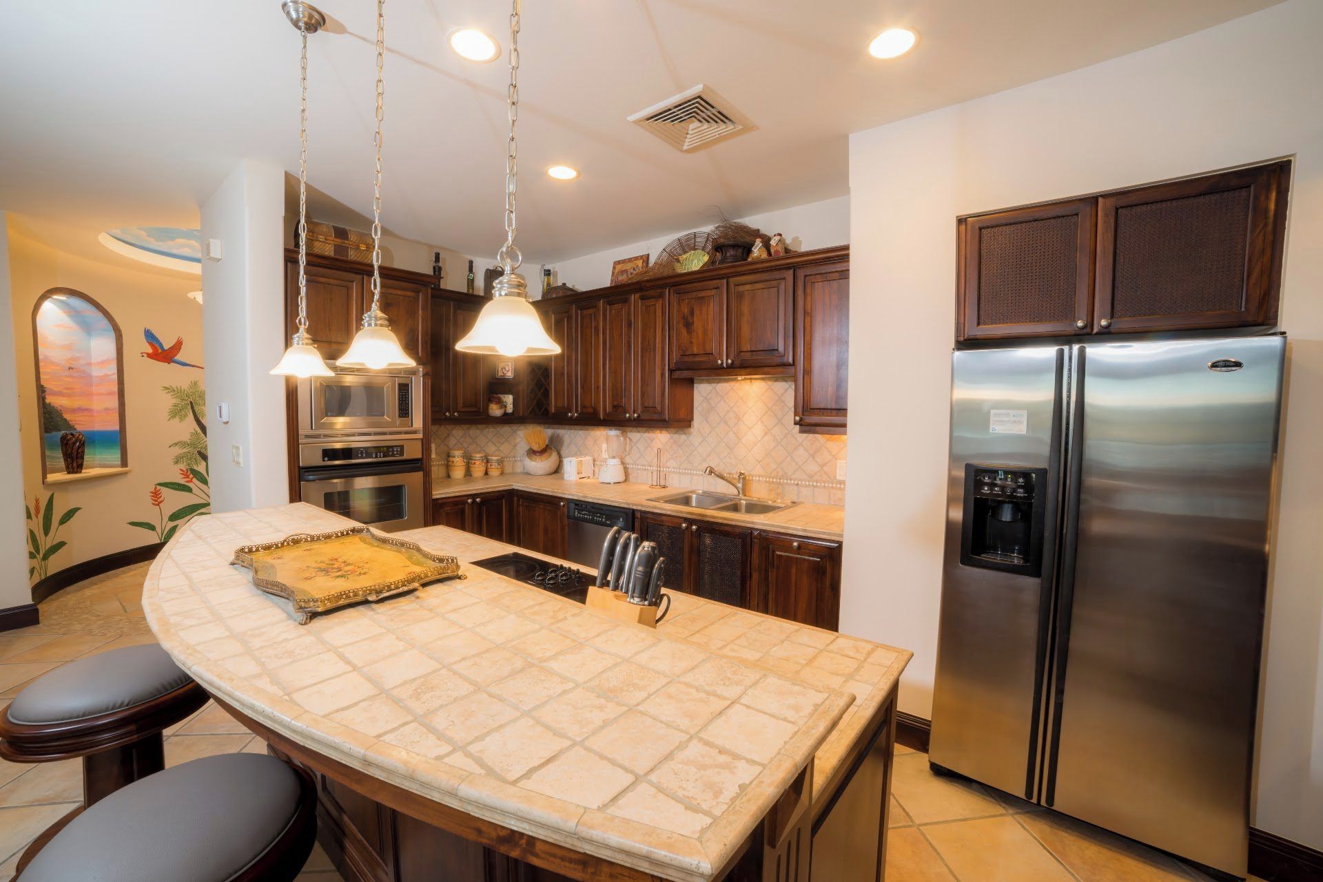 A kitchen with a central island, stainless steel appliances, and pendant lighting.