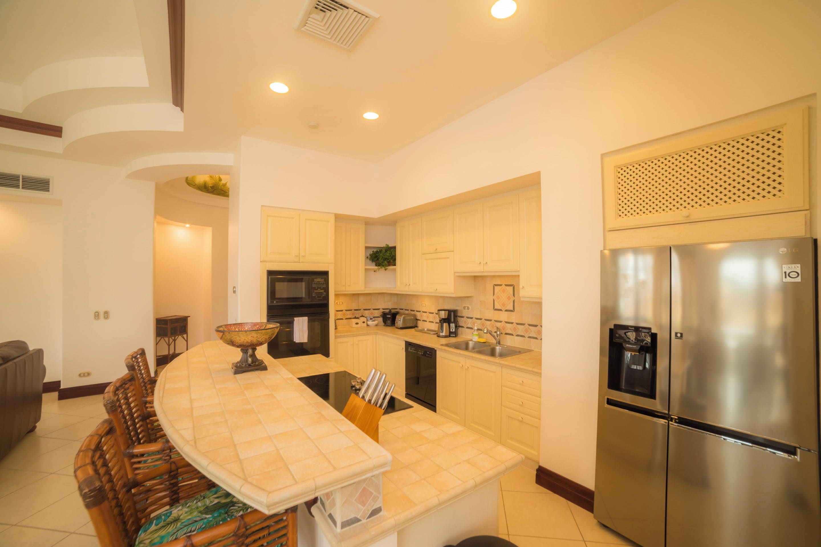 Cozinha moderna com ilha central, eletrodomésticos de aço inoxidável e armários em tons claros.