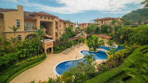 Un complejo turístico con varias edificaciones, una piscina central y exuberante jardinería.