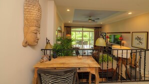 Zona pranzo con tavolo in legno, sedie e una grande scultura di testa di Buddha sulla parete.