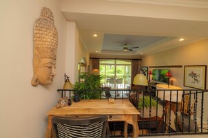 Un comedor con una mesa de madera, sillas y una gran escultura de cabeza de Buda en la pared.