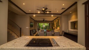 A modern kitchen with a granite countertop, built-in stove, and ceiling fans. - Vista Bahia 3D 3 bdr Ocean View in Los Suenos (Jacó)