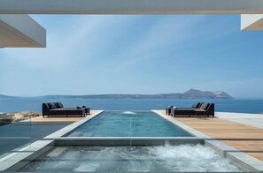 Une piscine à débordement offrant une vue sur la mer et une montagne au loin.