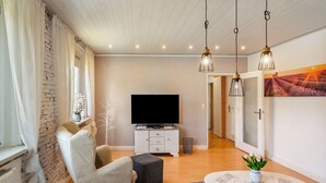 Una sala de estar moderna con un televisor de pantalla plana, una mesa de comedor con un florero y un ventanal con cortinas.