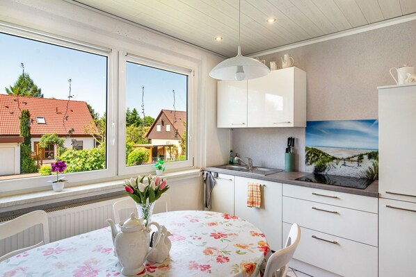 Eine Küche mit weißen Schränken, einem Spülbecken und einem Fenster mit Blick auf Häuser und Grünflächen.