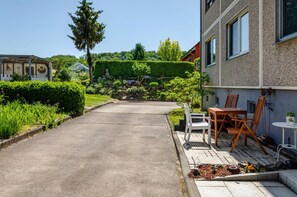 A paved pathway leading to a building with a garden area, a bench, and a table with chairs. - Holiday Apartment by the Herreder Forest (Nordhausen)