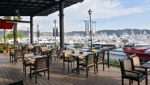 An outdoor dining area with tables and chairs, overlooking a marina with numerous boats. - Veranda 3G 2 bdr Garden View in Los Suenos (Jacó)