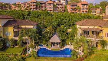 A resort with multiple-story buildings, a central swimming pool, and lush greenery.